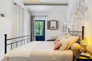 Une chambre à coucher avec un lit, une table de chevet, une lampe et une vue sur l’extérieur.