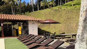 A beachside area with wooden loungers, a small kiosk, and a palm tree. - La Escondida Finca Hotel 12 minutes from the airport int JMC rionegro(MEDELLIN) (Guarne)