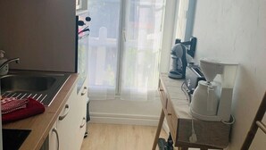 Una cocina pequeña con un lavabo, armarios y una cafetera sobre una mesa.