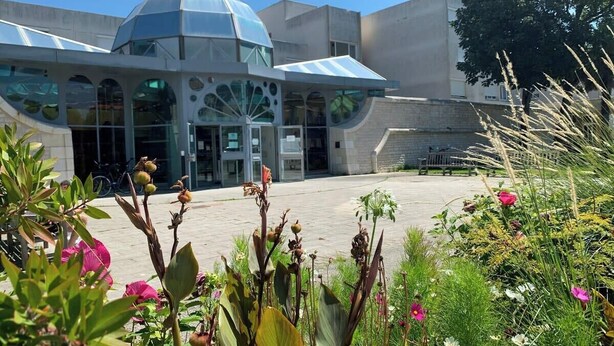 Un edificio moderno con un diseño arquitectónico único, que presenta una gran cúpula de vidrio y múltiples accesos.