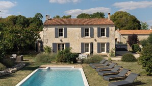 A stone building with a swimming pool and lounge chairs. - In the Perrines garden, in the heart of Aunis (Marsais)
