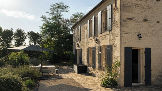 A stone building with a patio area, outdoor seating, and a gravel path. - In the Perrines garden, in the heart of Aunis (Marsais)