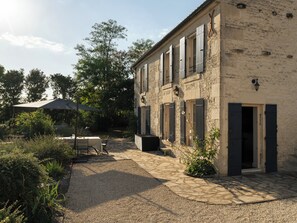 A stone building with a patio area, outdoor seating, and a gravel path. - In the Perrines garden, in the heart of Aunis (Marsais)
