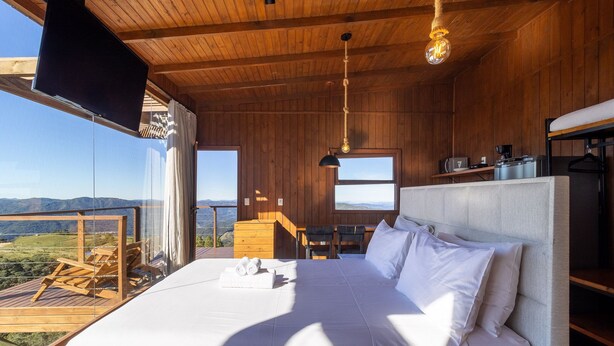 A bedroom with a large bed, a wooden ceiling, a TV, and a view of the outdoors. - Romantic Cabin With Amazing View Vst002 (Anitapolis)