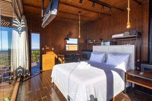 Un dormitorio con una cama grande, techo de madera y vistas a través de una puerta de cristal.