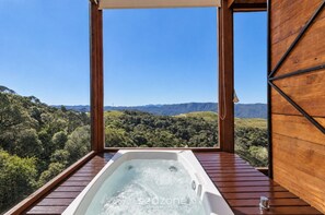 Un bain à remous avec une terrasse en bois et une vue sur un paysage montagneux.