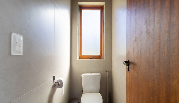 Un baño con inodoro, ventana y puerta de madera.