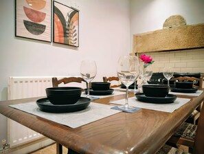 A dining table set with black bowls and wine glasses, a radiator, and abstract art on the wall. - 4 The Croft (Hexham)