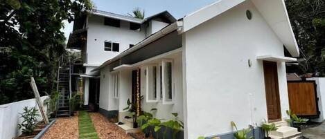 A modern two-story house with a white exterior, a sloped roof, and a small front porch.