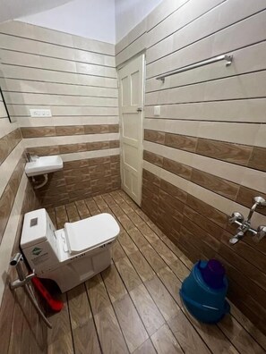 A small bathroom with a toilet, a sink, and a shower area. - Little Chandhana Guest House (Kottayam)