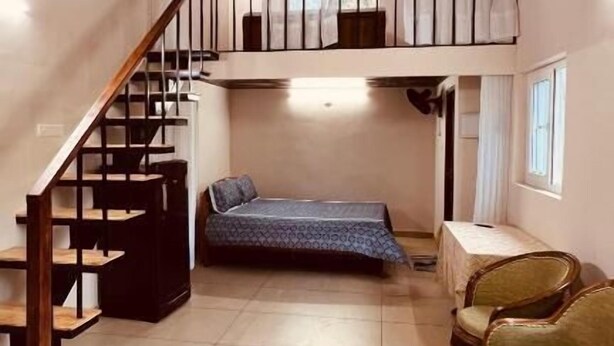 Une chambre de style « loft », avec un escalier, un lit, un canapé et une fenêtre.