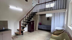 Un vaste espace de vie doté d’un haut plafond, d’un escalier, d’un canapé et d’un lit.