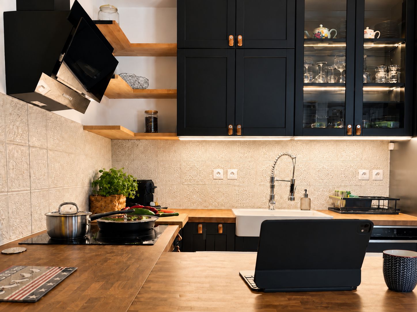 A modern kitchen with dark cabinets, a wooden countertop, a sink, and a stove.