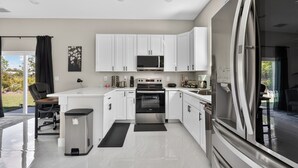 Una cocina moderna con gabinetes blancos, electrodomésticos de acero inoxidable y un tapete negro.