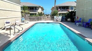 A swimming pool with a 5 ft depth marker, surrounded by lounge chairs and a fence. - Spacious • Walk to Beach • Pool & Lake Padre Views • Fishing Dock [6 night min.] (Corpus Christi)