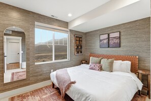 Une chambre dotée d’un grand lit, d’une fenêtre donnant sur l’extérieur et d’un mur décoré avec du bois.