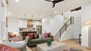 A spacious living area with a sofa, coffee table, and a staircase leading to an upper floor. - Deer Valley Basecamp with Hot Tub and Views (Heber City)