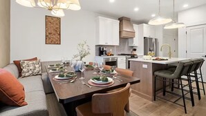 A modern kitchen with white cabinets, a central island, and pendant lighting. - Deer Valley Basecamp with Hot Tub and Views (Heber City)