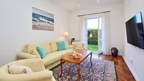 A living room with a sofa, a coffee table, a TV, and a view of the outdoors. - Green Horizon - One Bedroom Apartment, Sleeps 4 (Dubrovnik)