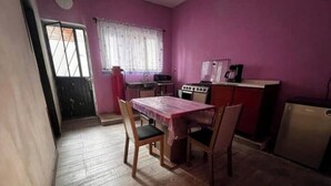 A small kitchen with a table and chairs, a window with curtains, and a door leading outside.