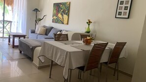 Ein Essbereich mit einem Tisch für vier Personen, einer Couch und einem Bild an der Wand.
