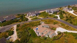 Luchtbeeld van een kustgebied met huizen, een weg en een strand.