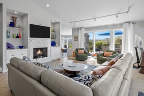 A spacious living room with a fireplace, comfortable seating, and a view of the outdoors. - STUNNING TRURO BAY VIEW 3 BDR,3 BATH PRIVATE HOME IN SECLUDED COMMUNITY (Truro)