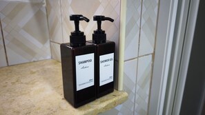 Deux flacons noirs de shampoing et de gel douche sont posés sur un comptoir de couleur beige.