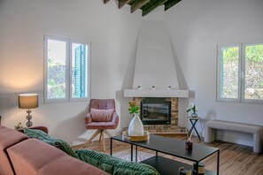 Ein Wohnzimmer mit Kamin, einer Couch, einem Sessel und einem Tisch.