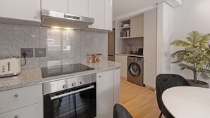 Eine kompakte Küche mit eingebautem Ofen, einem Toaster und einer Waschmaschine.