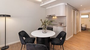 Eine moderne Küche mit weißen Schränken, einem runden Esstisch mit zwei schwarzen Stühlen und einer Stehlampe.