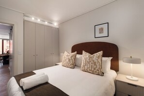 Habitación de hotel ordenada con una cama grande, mesitas de noche, un escritorio y un cuadro en la pared.