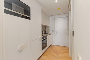 A modern kitchen with white cabinetry, a built-in oven, and a microwave. - Dolce Vita | Designer Sea Point Apartment (Cape Town)