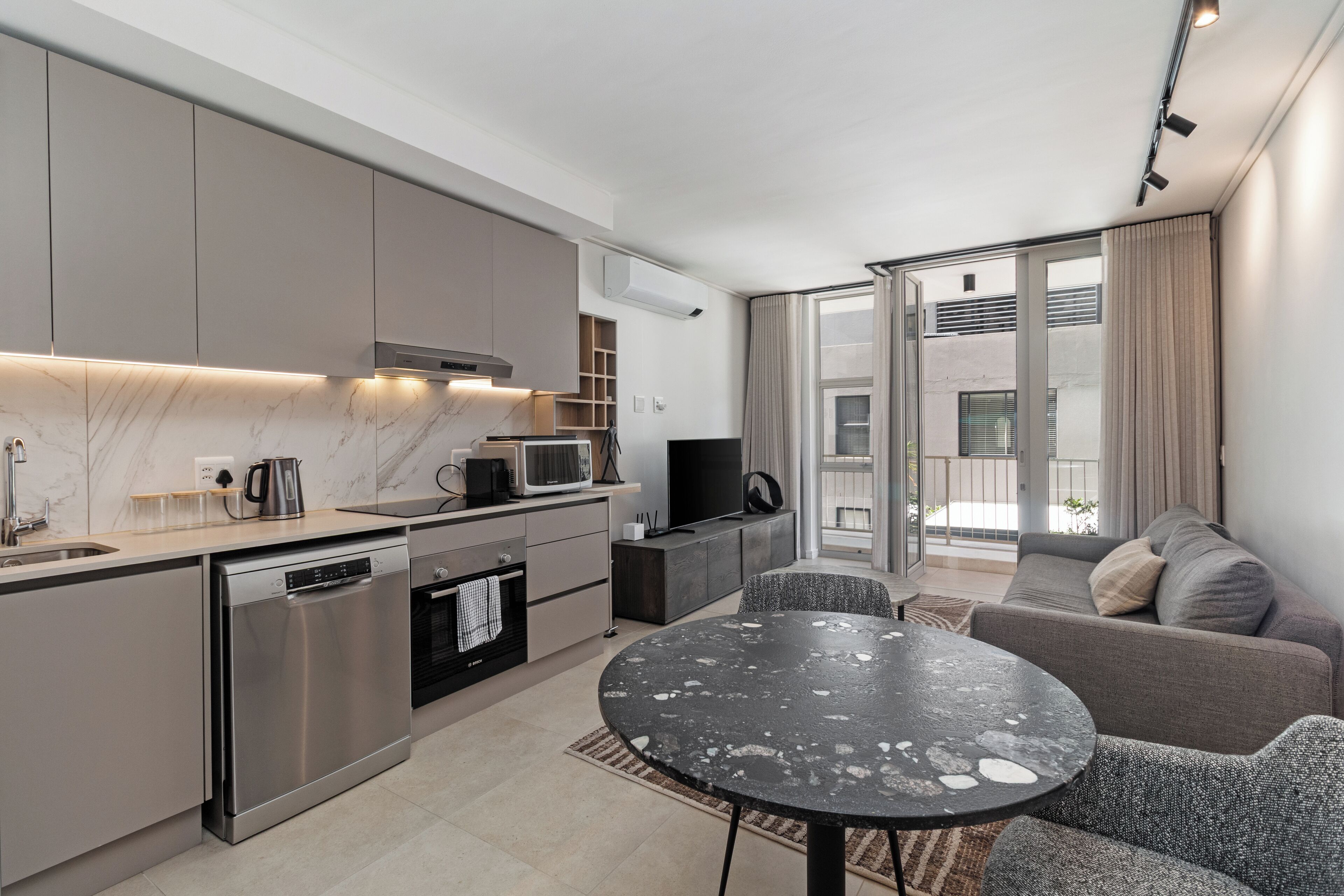 Una cucina moderna dotata di lavastoviglie, forno a microonde e zona pranzo con tavolo rotondo.