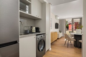 A compact kitchen with a washing machine, a microwave, and a coffee maker. - Dolce Vita | Sleek Apartment (Cape Town)