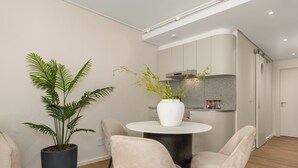 Moderni keittiö, jossa on valkoinen työtaso, sisäänrakennettu liesi ja harmaa välitilan laatoitus.