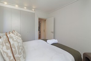 Une chambre d’hôtel avec un lit, une armoire et une salle de bain, visibles à travers une porte ouverte.