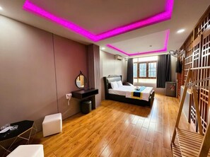 A modern bedroom with a bed, bedside table, and a small seating area. - Kim Linh Hotel  (Ho Chi Minh City)