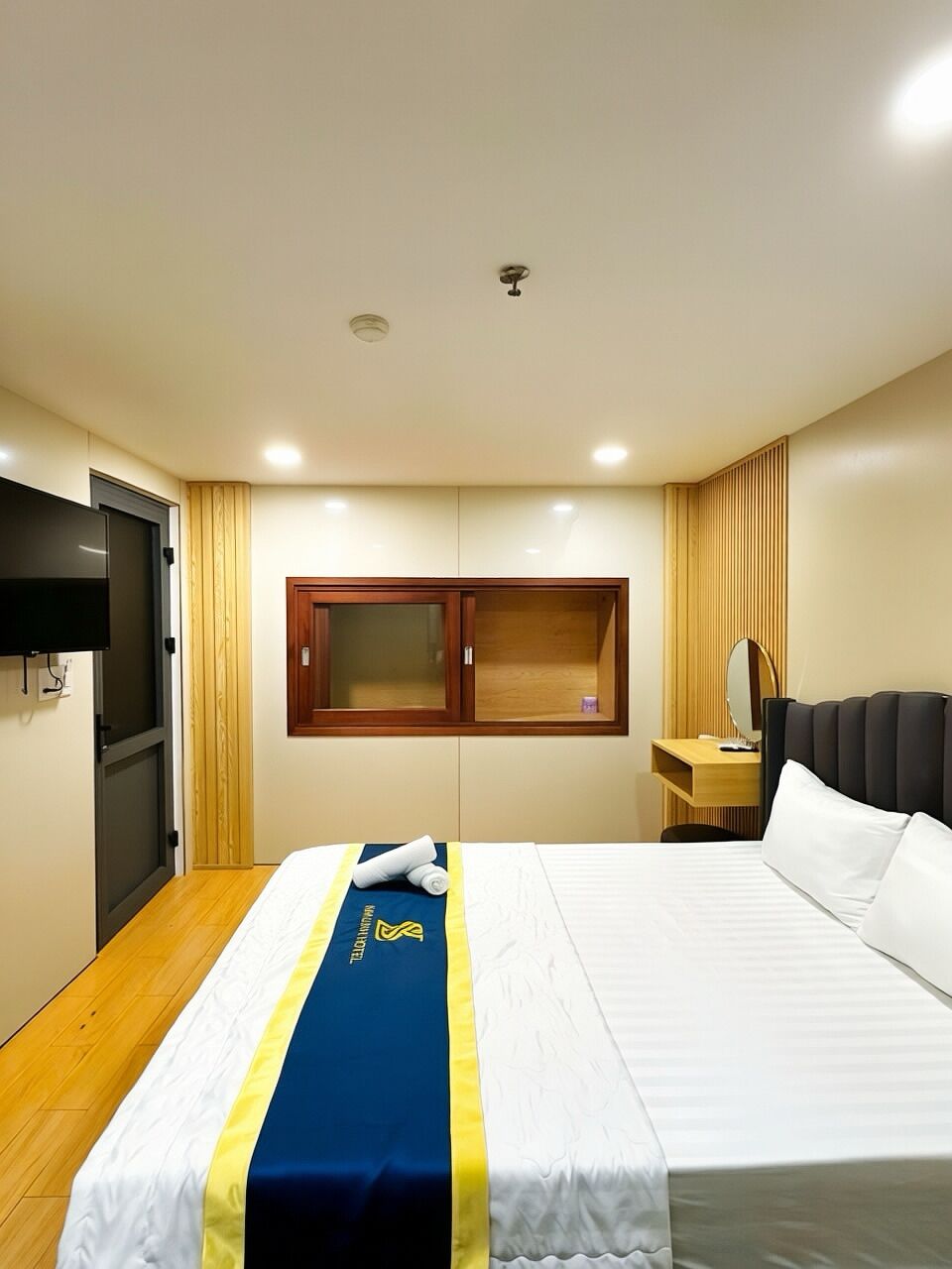 A hotel room with a bed, a TV, a desk, and a window.