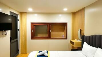 A hotel room with a bed, a TV, a desk, and a window.
