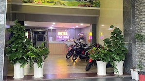 A hotel entrance with a reception desk, neon sign, and potted plants. - Kim Linh Hotel  (Ho Chi Minh City)