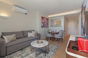 A modern living room with a grey sofa, a marble coffee table, and a dining area with a round table and chairs. - Dolce Vita | Prime Sea Point Location (Cape Town)