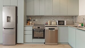 Une cuisine moderne dotée d’appareils électroménagers en acier inoxydable, de plans de travail en granit et de meubles de couleur claire.