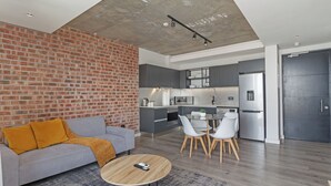 A modern living room with a grey sofa, a coffee table, and a brick wall. - Stylish Stay at The Signature | Central and Modern (Cape Town)