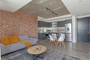 A modern living room with a grey sofa, a coffee table, and a brick wall. - Stylish Stay at The Signature | Central and Modern (Cape Town)