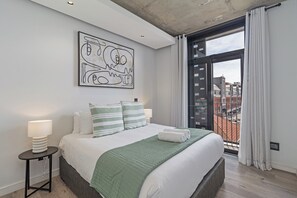 A modern bedroom with a large bed, a view of the city through a balcony, and a unique abstract artwork on the wall. - Stylish Stay at The Signature | Central and Modern (Cape Town)