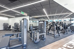 A gym with various exercise equipment, including weight machines and free weights. - One Rosebank | Chic City Hideaway (Johannesburg)