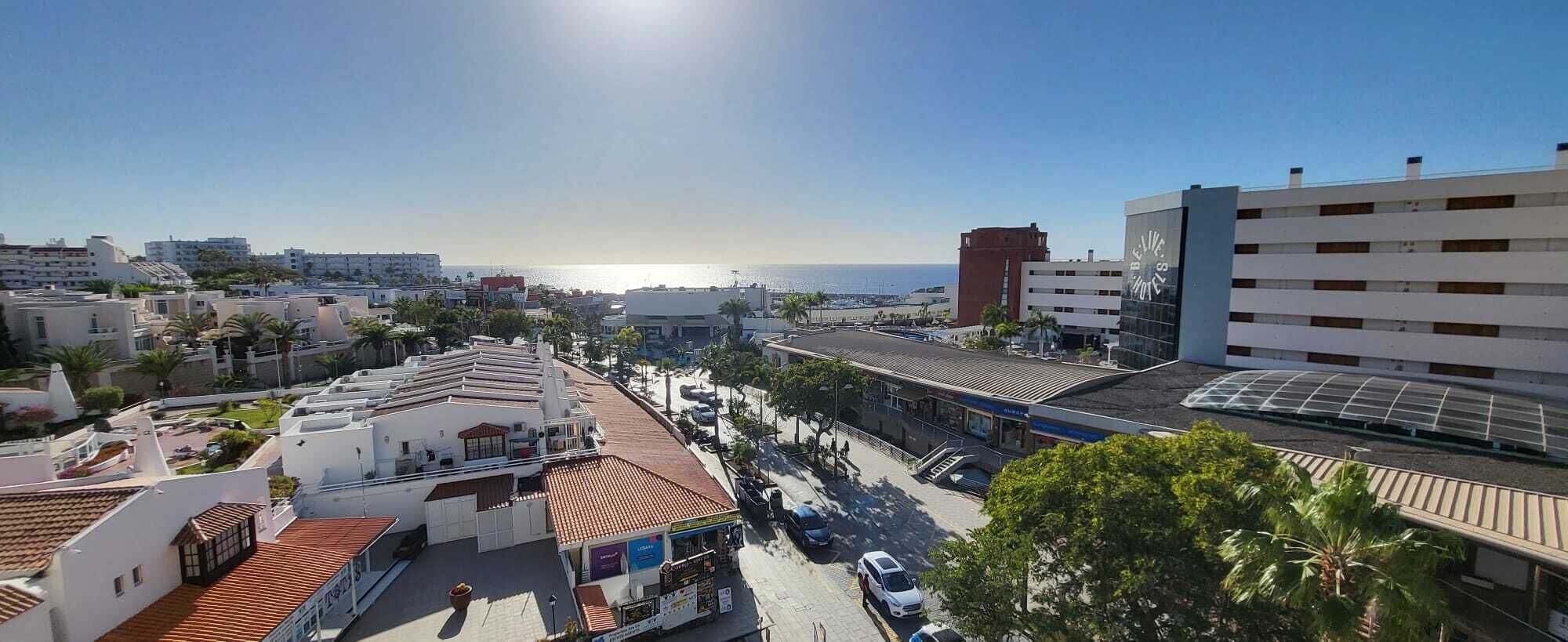 A coastal urban area with a mix of residential and commercial buildings, including a hotel with a red-tiled roof and a large glass facade.