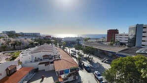 Ett stadsområde beläget vid kusten, med en blandning av bostads- och affärsbyggnader, inklusive ett hotell med ett rött tegeltak och en stor glasfasad.
