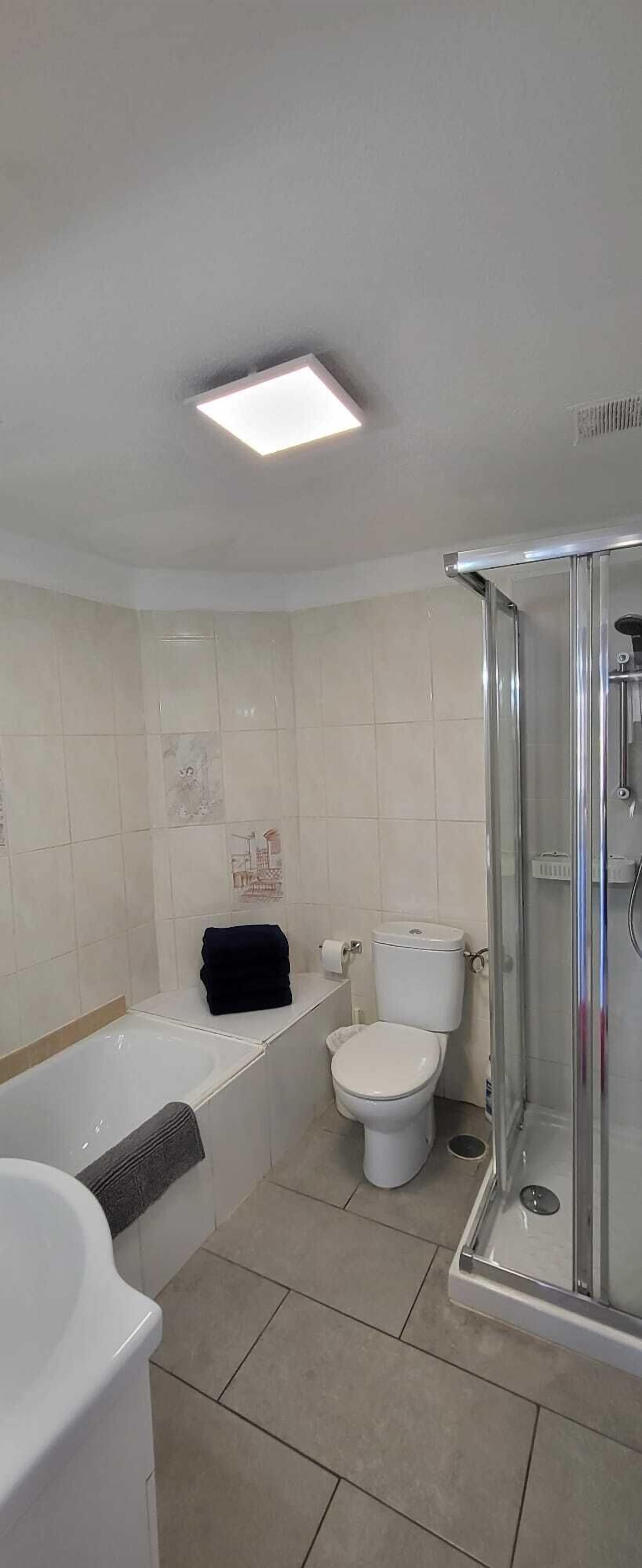 A bathroom with a bathtub, toilet, and glass-enclosed shower.